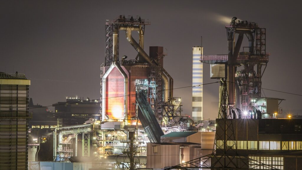 power Generation plant emitting steam and surrounded by electrical transmission lines.