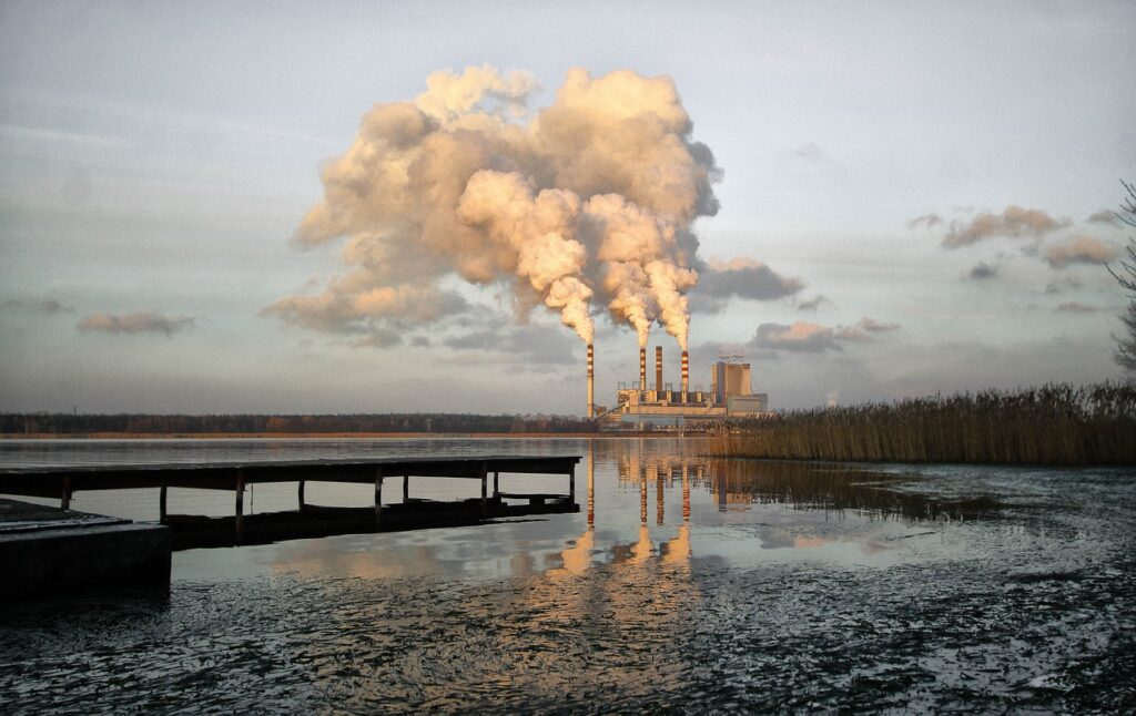 power Generation plant emitting steam and surrounded by electrical transmission lines.