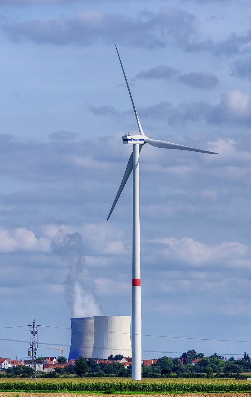 power Generation plant emitting steam and surrounded by electrical transmission lines.